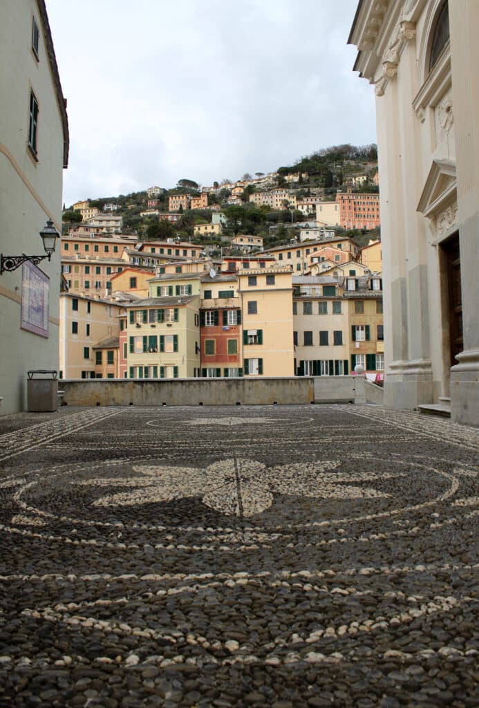 Maisons colorées et dallage de galets en Italie Dallage en galets noirs et blancs d'une place devant des maisons colorées en Ligurie, Italie.
